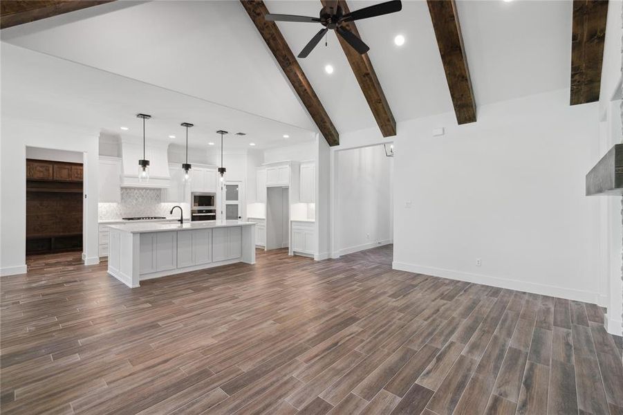 Unfurnished living room with ceiling fan, hardwood / wood-style flooring, and beam ceiling