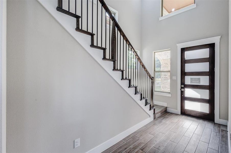 Foyer featuring stairs, wood finish floors, and a high ceiling