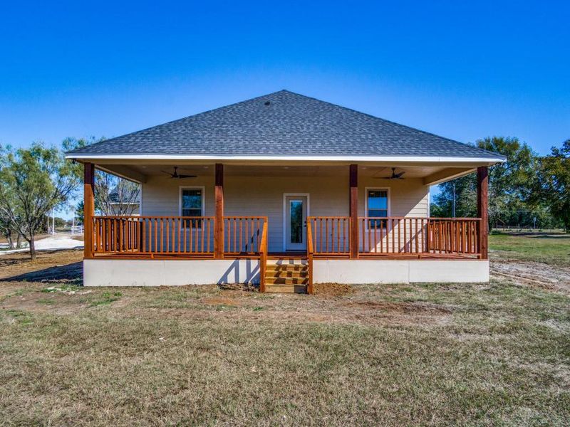 Rear view of property featuring a porch, ceiling fan, and a lawn