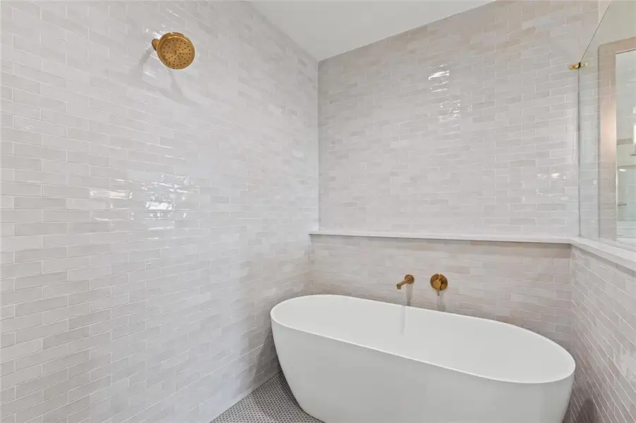 Bathroom featuring tile walls and a freestanding tub