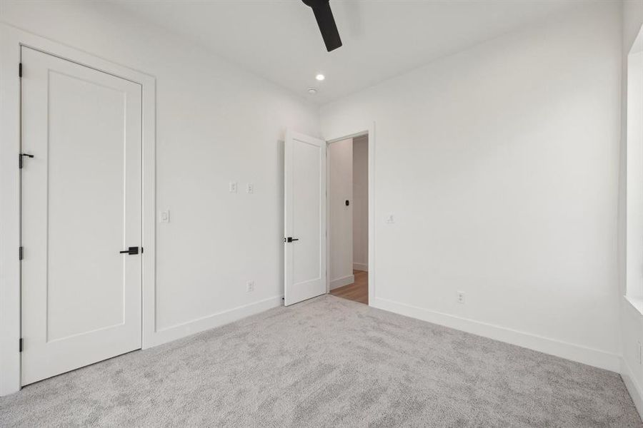 Unfurnished bedroom with light colored carpet and ceiling fan