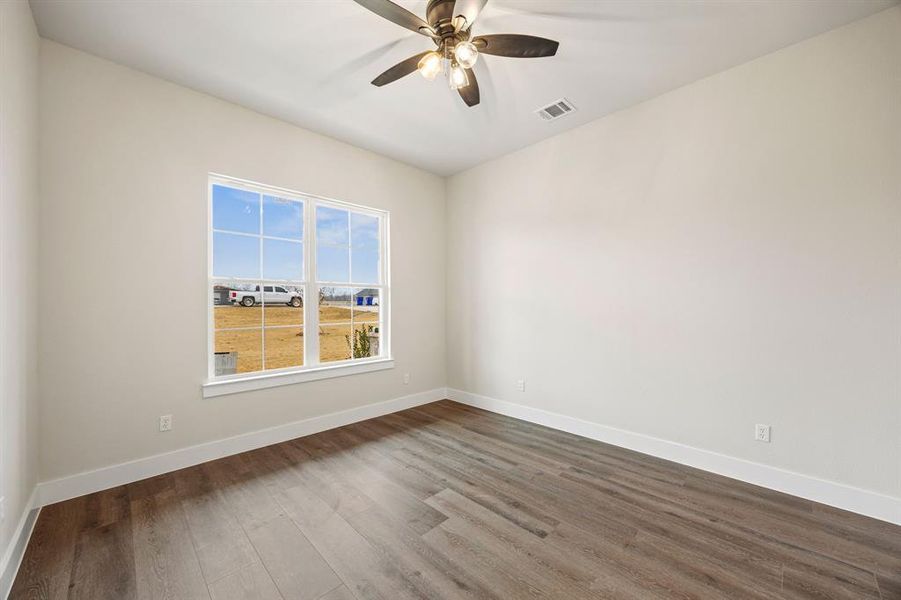 Empty room featuring dark wood-type flooring and a ceiling fan Empty room featuring dark wood-type flooring and a ceiling fan