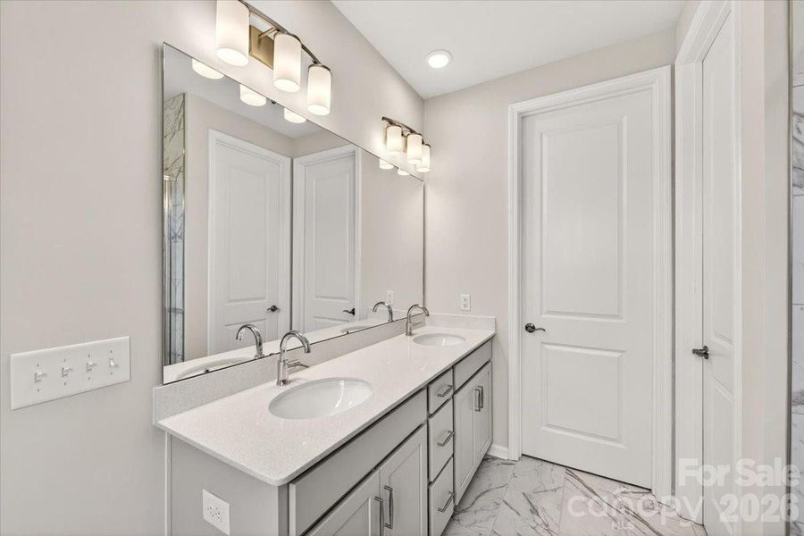 Dual vanity primary bathroom with white quartz countertops Dual vanity primary bathroom with white quartz countertops