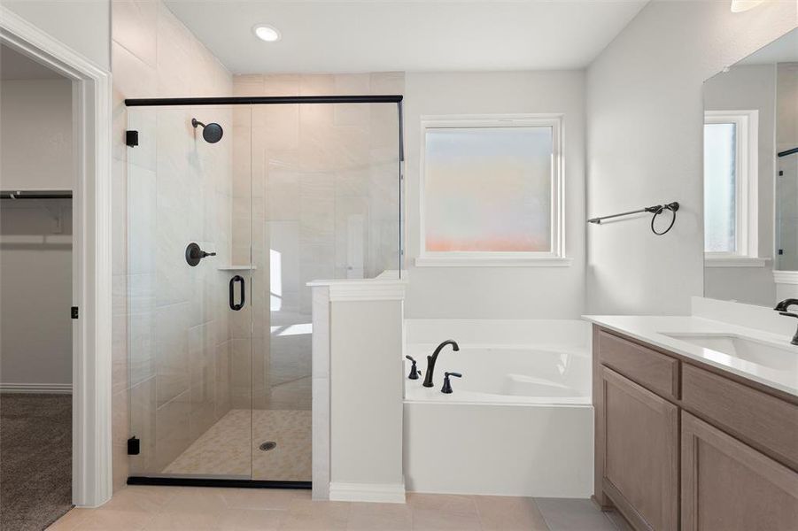 Full bathroom featuring a bath, vanity, a stall shower, a spacious closet, and light tile patterned flooring Full bathroom featuring a bath, vanity, a stall shower, a spacious closet, and light tile patterned flooring