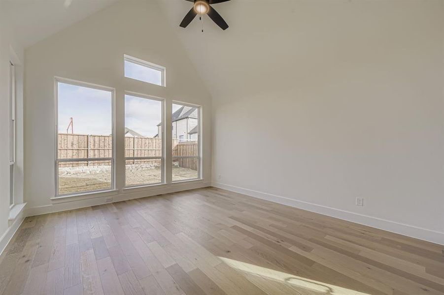 Spare room featuring high vaulted ceiling, light wood finished floors, and a ceiling fan