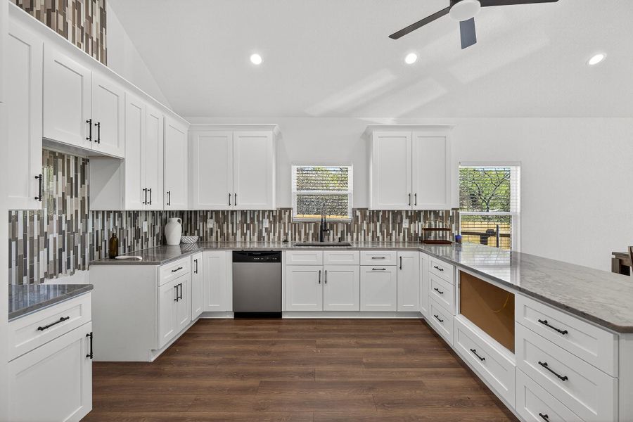 Kitchen with white cabinets, recessed lighting, dark wood-style flooring, healthy amount of natural light, and lofted ceiling Kitchen with white cabinets, recessed lighting, dark wood-style flooring, healthy amount of natural light, and lofted ceiling