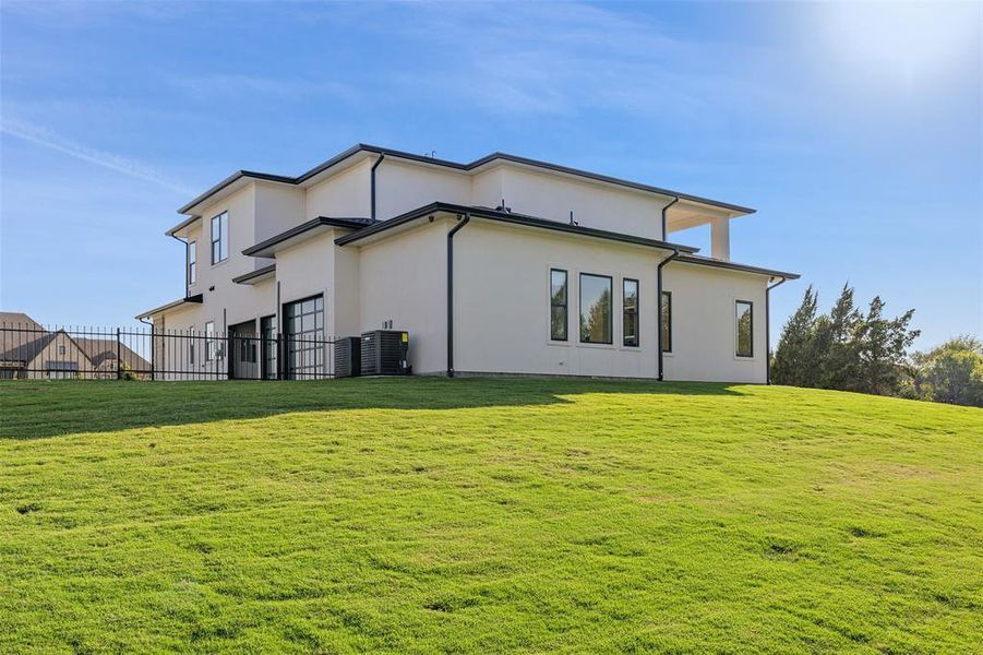 Rear view of house featuring cooling unit and a lawn