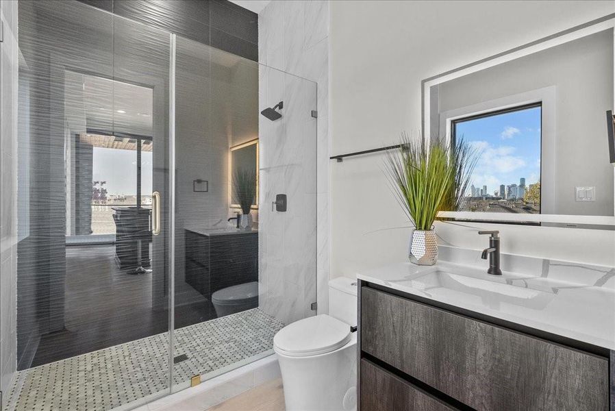 This modern bathroom features a sleek design with a glass-enclosed shower, stylish vanity, and large mirror. A window offers natural light and urban views, enhancing the space's contemporary feel. This modern bathroom features a sleek design with a glass-enclosed shower, stylish vanity, and large mirror. A window offers natural light and urban views, enhancing the space's contemporary feel.
