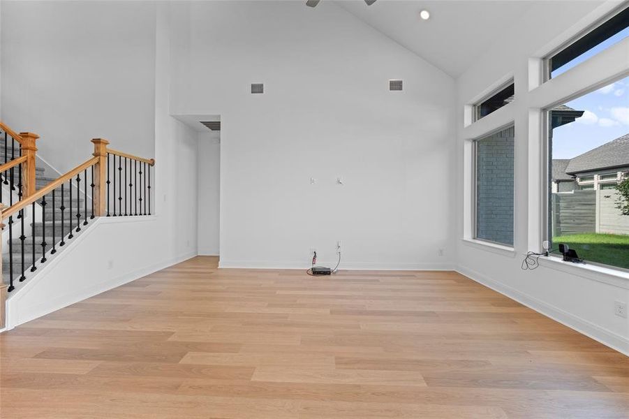 Empty room with light hardwood / wood-style flooring and high vaulted ceiling