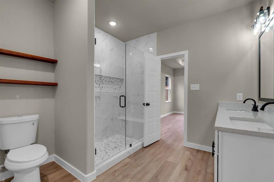 Bathroom with vanity, a shower with shower door, wood-type flooring, and toilet