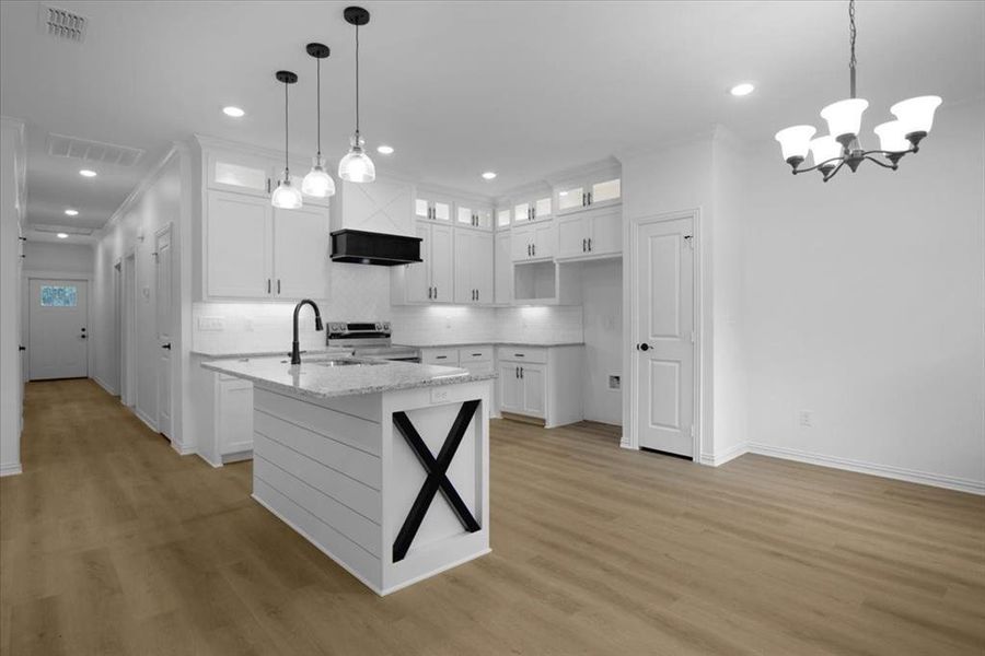 Kitchen with glass insert cabinets, ornamental molding, white cabinets, stainless steel range with electric cooktop, and an island with sink