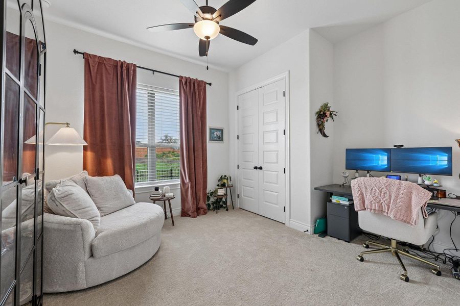 Carpeted room featuring a ceiling fan, a window with blinds and drapes, and a double-door closet with paneling