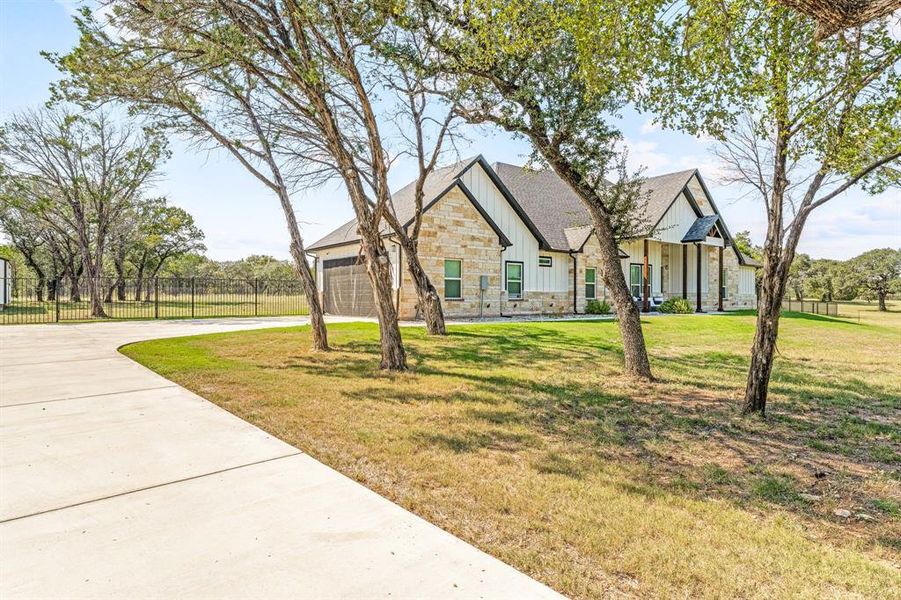 View of front facade featuring stone siding, board and batten siding, concrete driveway, an attached garage, and a shingled roof View of front facade featuring stone siding, board and batten siding, concrete driveway, an attached garage, and a shingled roof