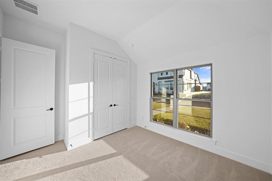 Unfurnished bedroom with carpet, vaulted ceiling, and a closet Unfurnished bedroom with carpet, vaulted ceiling, and a closet