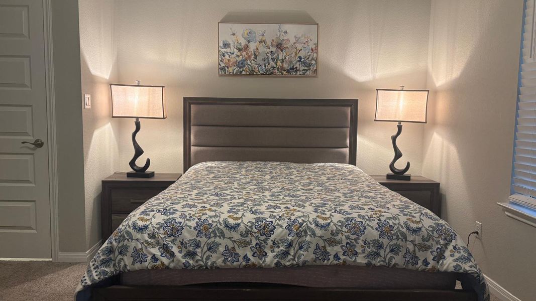 A well-lit bedroom features plush carpeting and convenient bedside tables.