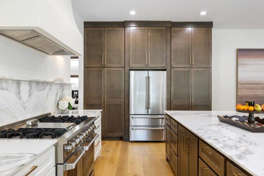 Culinary delights await in this modern kitchen featuring a high-end range, marble counters, and rich cabinetry. Culinary delights await in this modern kitchen featuring a high-end range, marble counters, and rich cabinetry.