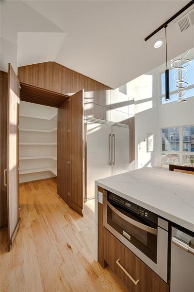 Kitchen featuring light hardwood / wood-style flooring, light stone counters, decorative light fixtures, and oven