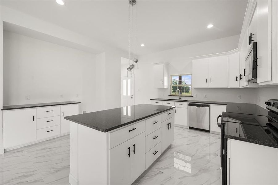 Kitchen featuring appliances with stainless steel finishes, light marble finish floors, recessed lighting, a center island, and white cabinetry Kitchen featuring appliances with stainless steel finishes, light marble finish floors, recessed lighting, a center island, and white cabinetry