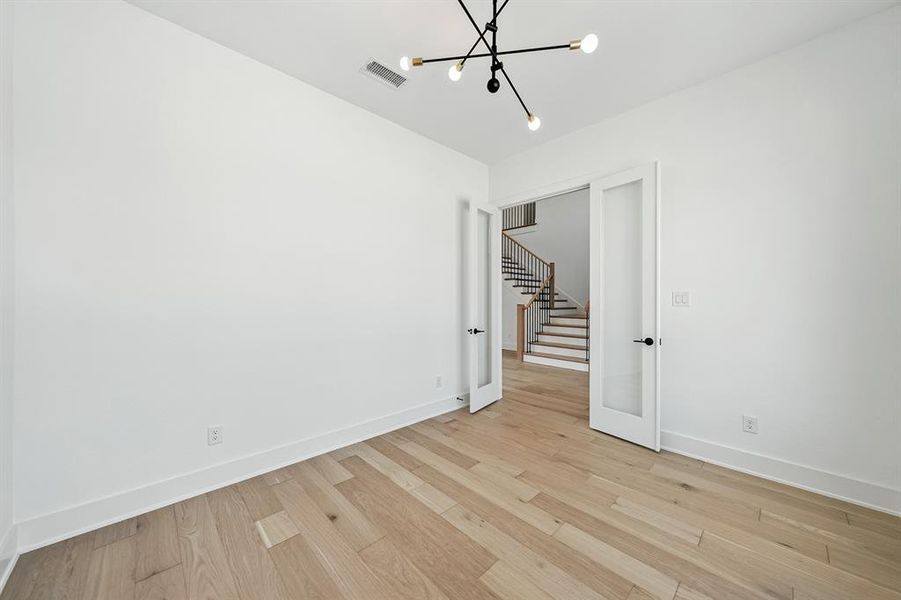 Empty room with light wood-style floors, stairs, and a chandelier