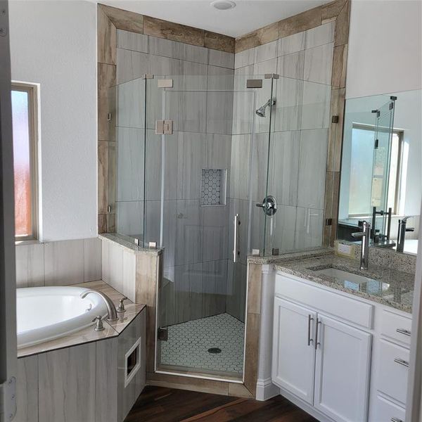 Bathroom featuring a wealth of natural light, independent shower and bath, wood-type flooring, and vanity