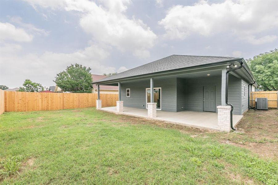 Rear view of property with a yard, central AC unit, and a patio