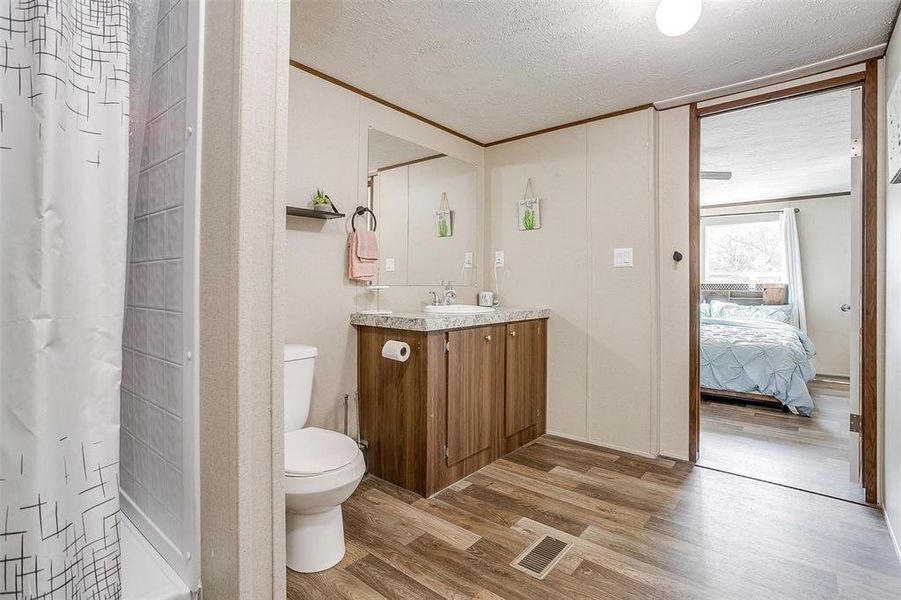 Bathroom featuring toilet, wood-type flooring, ornamental molding, a shower with curtain, and vanity