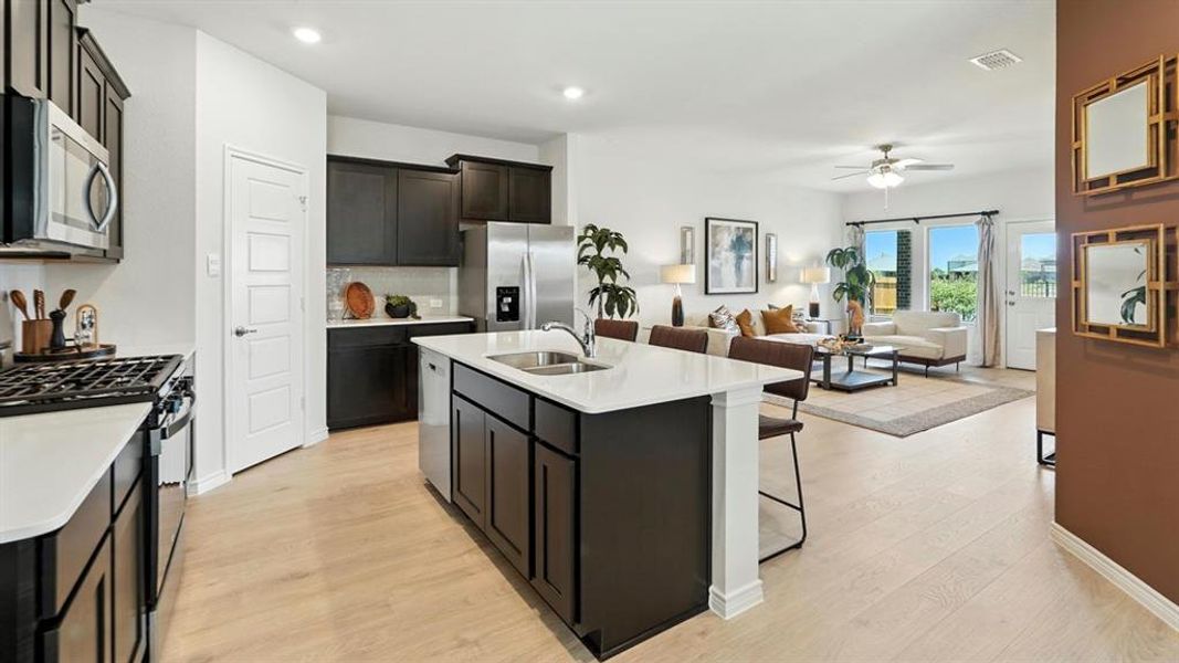 Kitchen featuring stainless steel appliances, an island with sink, light stone countertops, light wood finished floors, and recessed lighting Kitchen featuring stainless steel appliances, an island with sink, light stone countertops, light wood finished floors, and recessed lighting