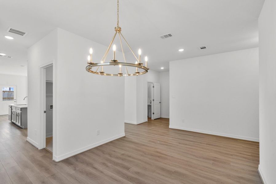 Elegant formal dining space with beautiful flooring that continues seamlessly throughout, highlighted by a unique light fixture that adds character and style.