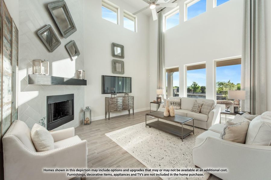 Living room with two-story ceiling, fireplace, hardwood floors, and large windows with natural light