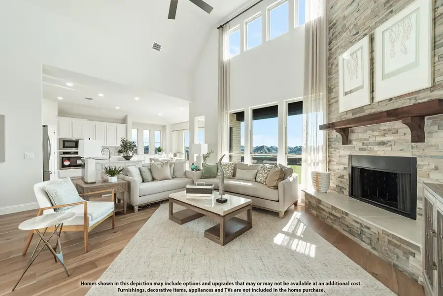Open living room with vaulted ceiling, stone fireplace, and open-concept kitchen in background Open living room with vaulted ceiling, stone fireplace, and open-concept kitchen in background
