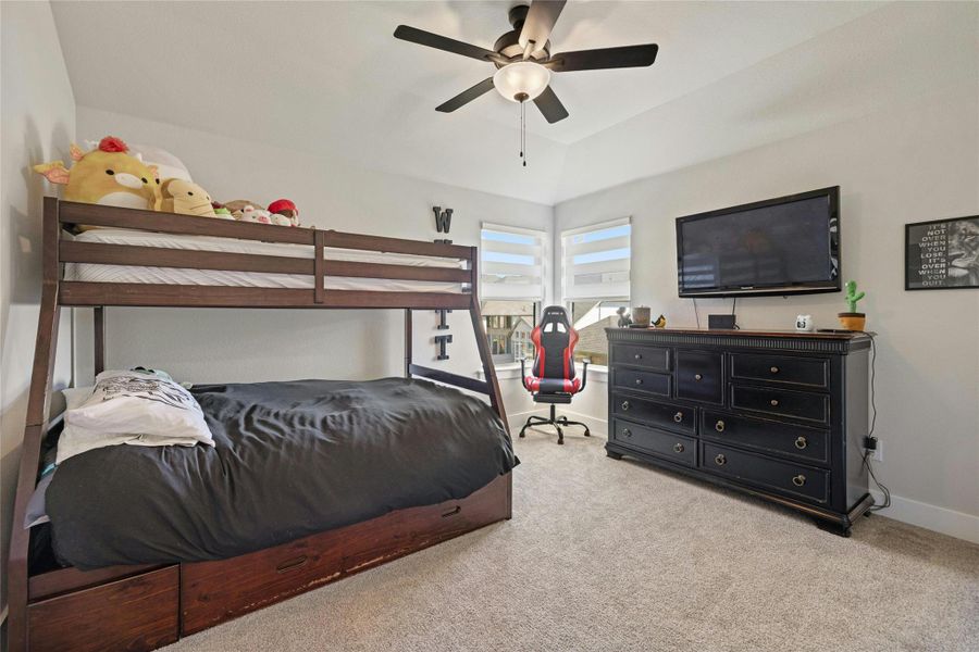 Bedroom featuring carpet floors, a ceiling fan, and vaulted ceiling Bedroom featuring carpet floors, a ceiling fan, and vaulted ceiling