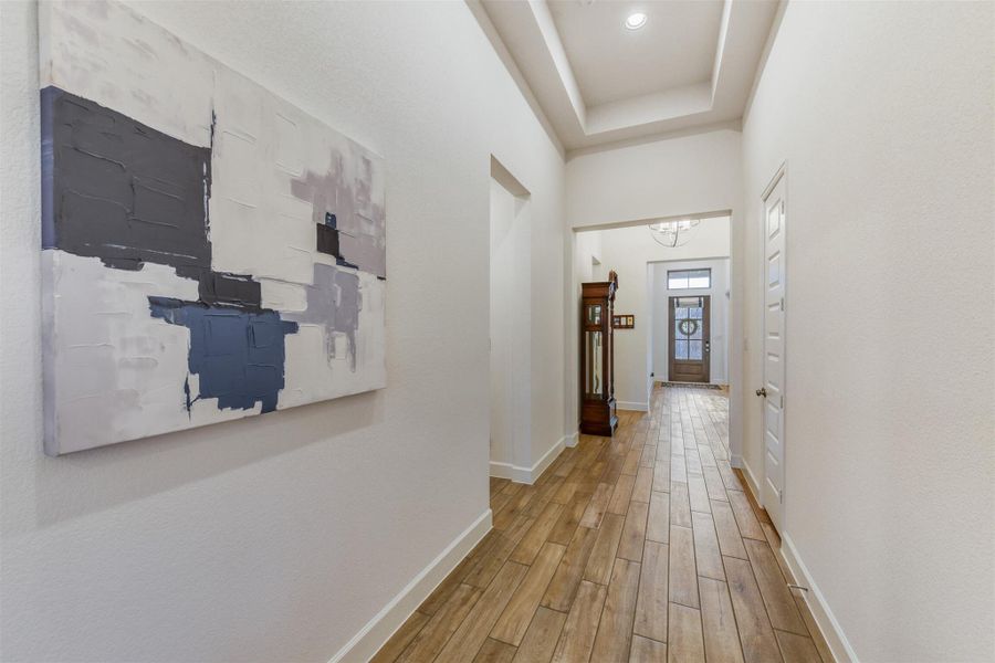 Corridor featuring light wood-style flooring and a raised ceiling