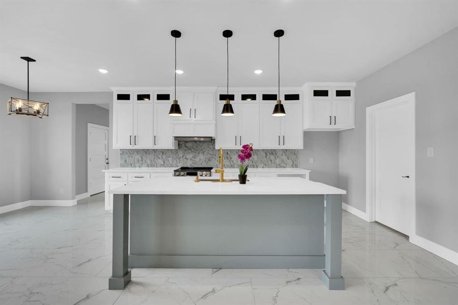 Kitchen with decorative backsplash, an island with sink, light tile patterned floors, and decorative light fixtures