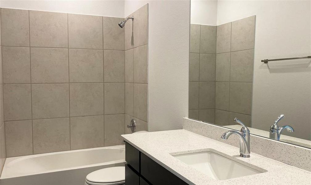 Full bathroom featuring vanity, toilet, and tiled shower / bath combo