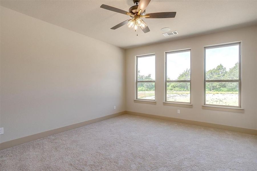 Unfurnished room with light colored carpet, visible vents, a ceiling fan, and baseboards