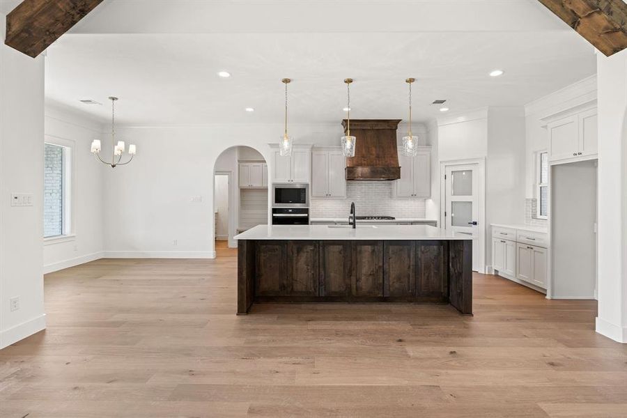 Kitchen featuring tasteful backsplash, wall oven, arched walkways, stainless steel microwave, and recessed lighting