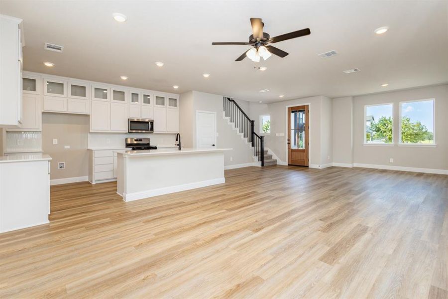 Unfurnished living room featuring light wood-style floors, recessed lighting, ceiling fan, and stairs