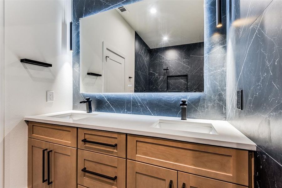 Full bathroom with double vanity, tile walls, recessed lighting, and a marble finish shower