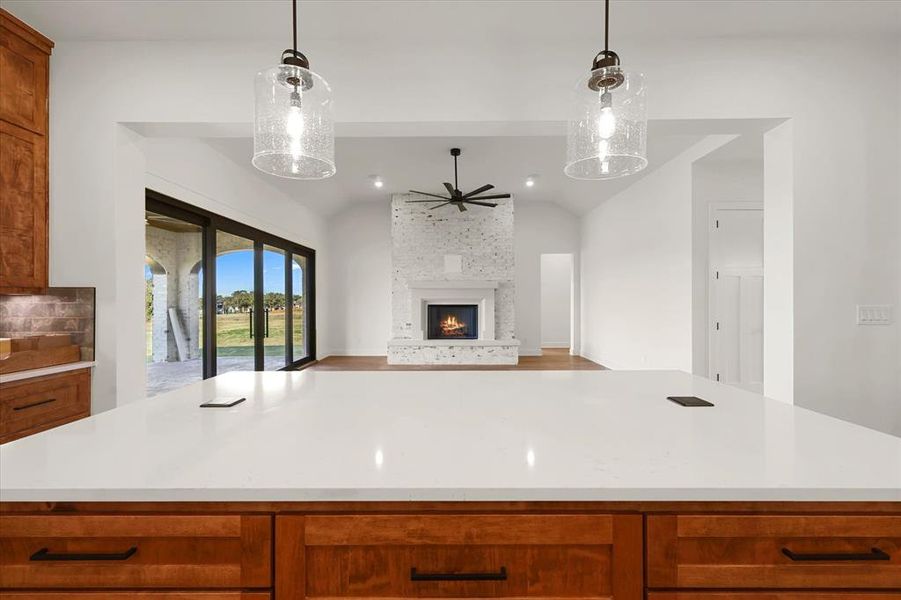 Kitchen featuring brown cabinets, decorative light fixtures, a kitchen island, vaulted ceiling, and recessed lighting