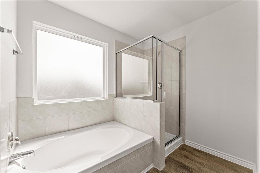 Full bathroom featuring a stall shower, a garden tub, and dark wood-type flooring Full bathroom featuring a stall shower, a garden tub, and dark wood-type flooring