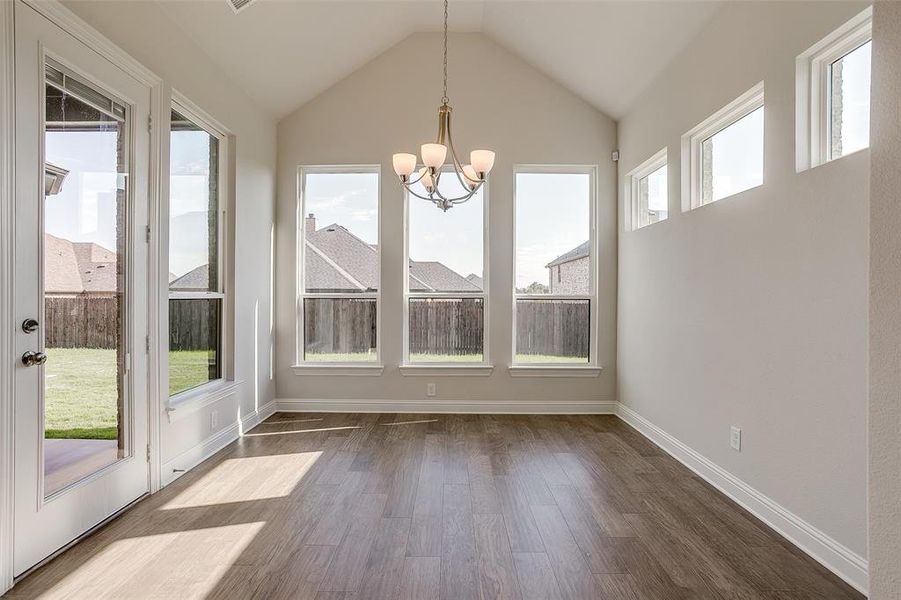 Unfurnished dining area with a chandelier, vaulted ceiling, and dark hardwood / wood-style flooring