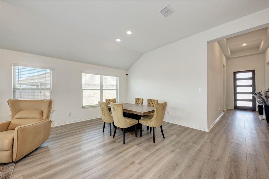 An inviting dining area offers generous natural light, vaulted ceilings, and durable plank flooring.
