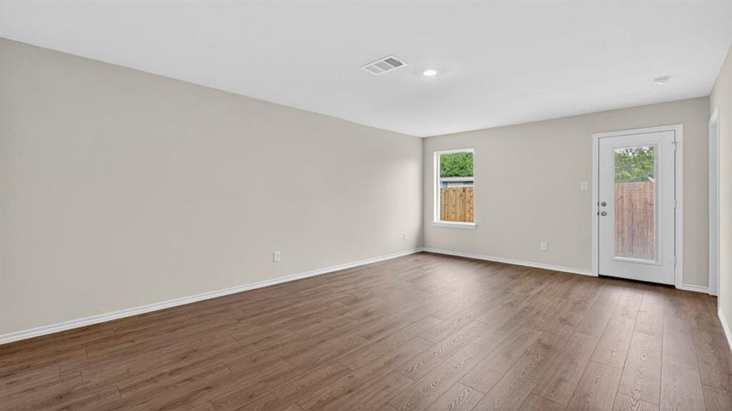 Spacious room featuring wood-finish flooring, light gray walls, white baseboards, and recessed lighting