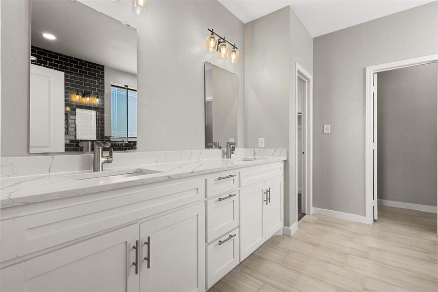 Bathroom with double vanity, a shower stall, and light wood-type flooring