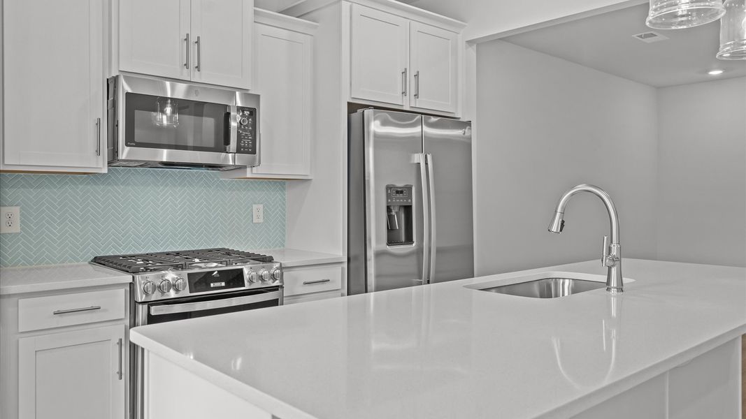 Elegant kitchen with large island and pendant lighting in this first-class DRB Homes design