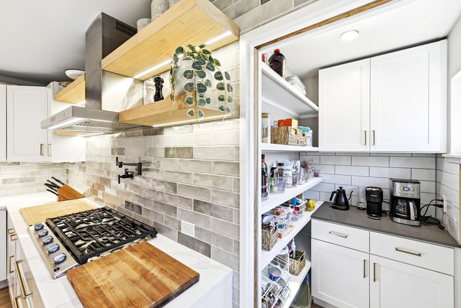 Kitchen featuring white cabinetry, open shelves, tasteful backsplash, stainless steel gas cooktop, and dark stone countertops