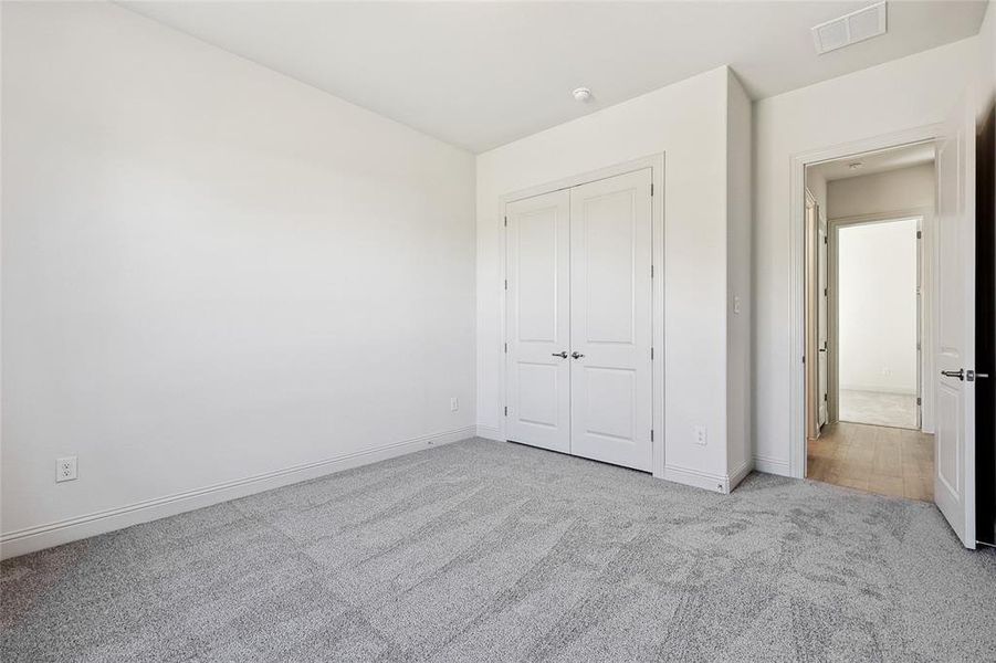 Unfurnished bedroom with light colored carpet and a closet