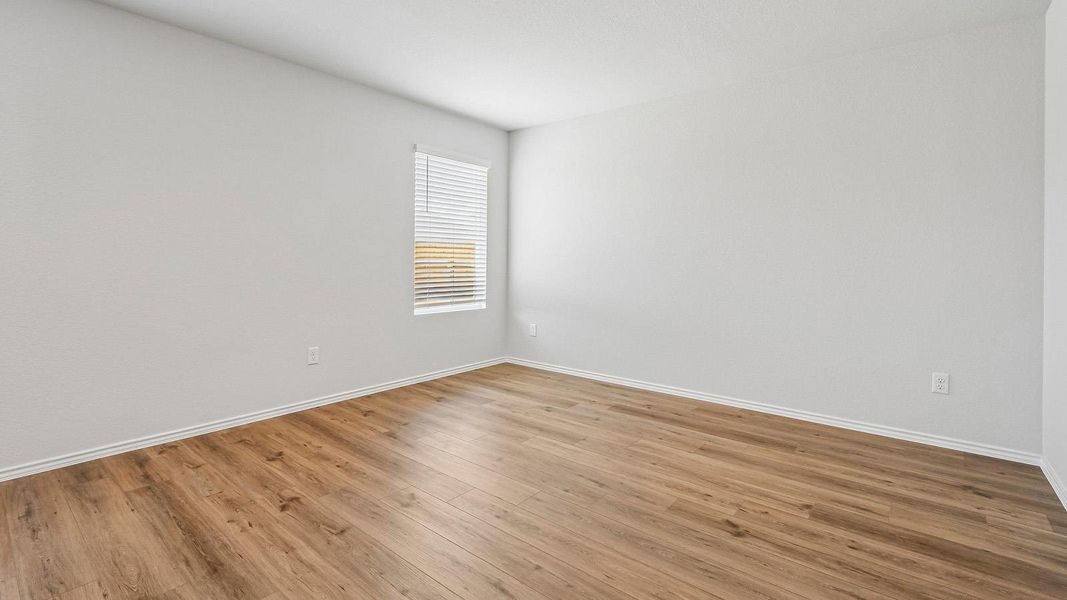 Natural light streams into this versatile space through a well-placed window, showcasing the inviting wood flooring.