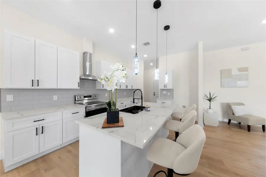 Kitchen featuring a kitchen island with sink, backsplash, a breakfast bar area, light stone countertops, and recessed lighting Kitchen featuring a kitchen island with sink, backsplash, a breakfast bar area, light stone countertops, and recessed lighting