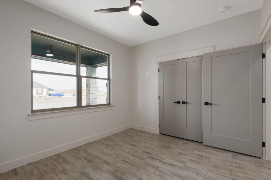 Unfurnished bedroom featuring light wood-style floors, ceiling fan, and a closet